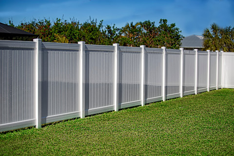 A white vinyl privacy fence surrounds a residential property. The solid panels create a clean and uniform boundary.