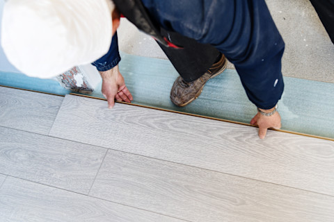 A pro is installing a new laminate wooden floor.