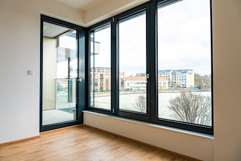 A tilt and turn window door system is shown in a modern interior. The window is open to demonstrate its function.