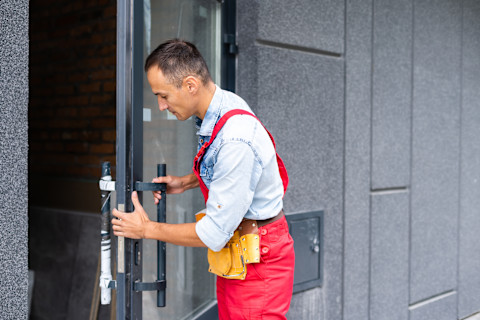 This image shows a locksmith wearing overalls fitting a lock on an internal door