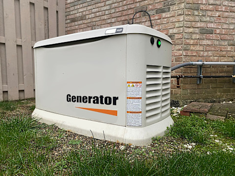 This image shows a backup generator outside on the grass of a residential property, storing enough energy to power the whole home during a power outage. 

