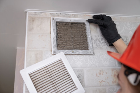 A tradesperson is clearing out an air duct.