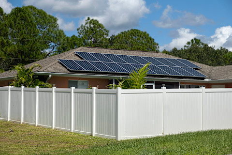 A white vinyl fence surrounds a private residential property. The fence provides privacy and a clean visual boundary.