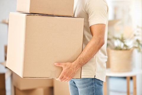 This image shows a person carrying two stacked cardboard boxes, suggesting they are moving house.