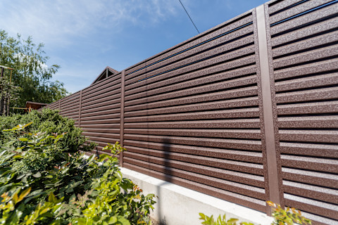 Prefab wooden fence panels are arranged horizontally. The wood has a natural finish and clean construction.