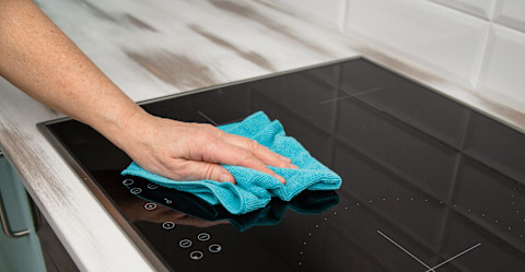Microfibre cloth being wiped over a glass cooktop