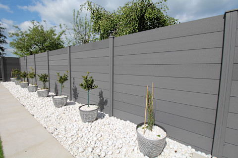Prefab wooden fence panels are arranged horizontally. The wood has a natural finish and clean construction.