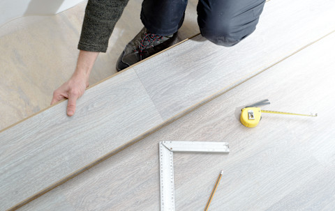 A pro is installing a new laminate wooden floor.