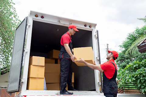 Two men are moving boxes out of a moving van.