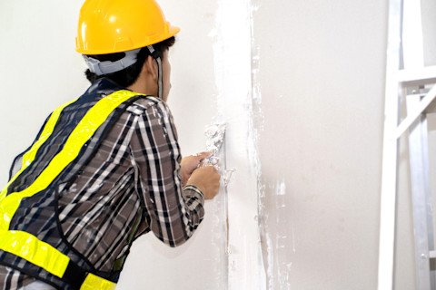 A man is installing drywall into a new home.