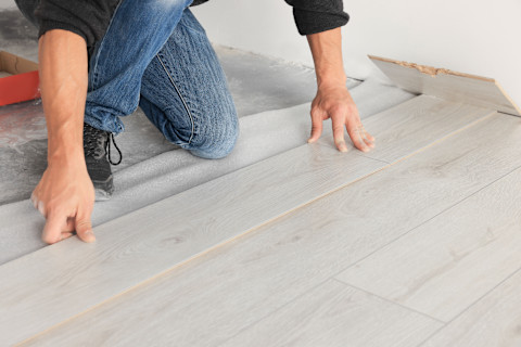 A pro is installing a new laminate wooden floor.