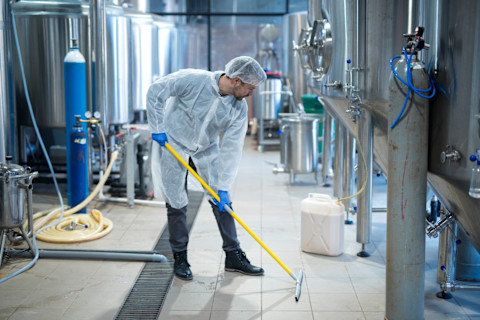 Worker in protective suits cleans an industrial area