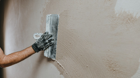 This image shows a builder applying plaster to a wall. 