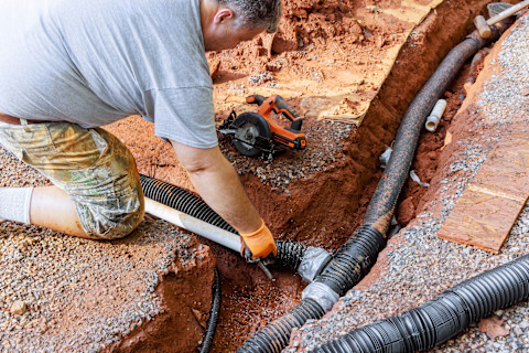 A man is installing a new drainage system into a house.