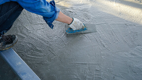 A tradesperson is smoothing over some new concrete