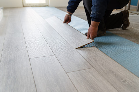 A man is installing a new laminate wooden floor.