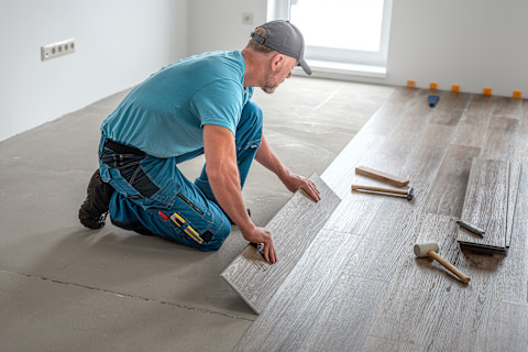 A man is installing a new wooden floor.
