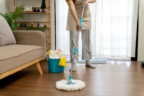 A woman cleaner using a mop to clean a wooden floor