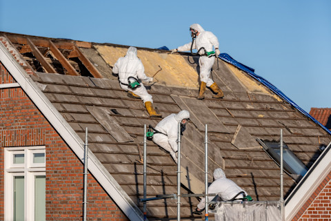 Team of certified professionals performing safe asbestos roof removal on a residential building. Example of expert asbestos abatement services ensuring health and environmental protection