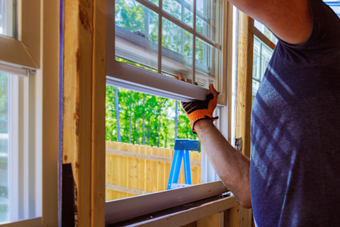 A worker installs a new window into a window frame.