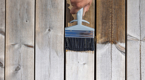 Applying deck sealant with a brush.