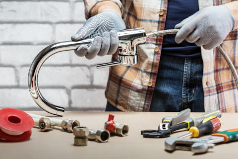 A closeup of a plumber making a faucet with different tools and elements.