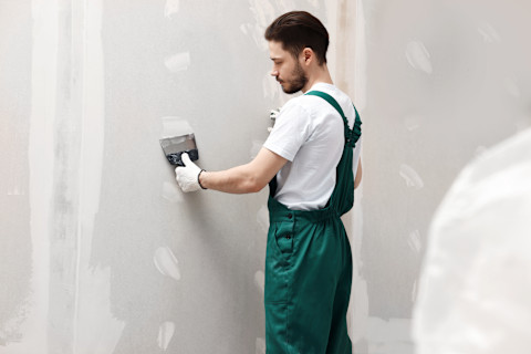 A man is installing drywall into a new home.