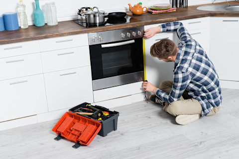 A professional is fitting a new oven in a kitchen.