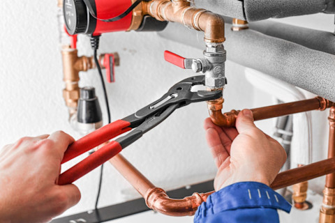 A plumber works on a copper water pipe installation as part of a plumbing service.