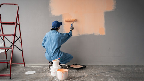 We see a man painting an indoor wall in a Canada home.