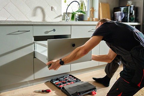 A professional is fitting a new kitchen cabinet.